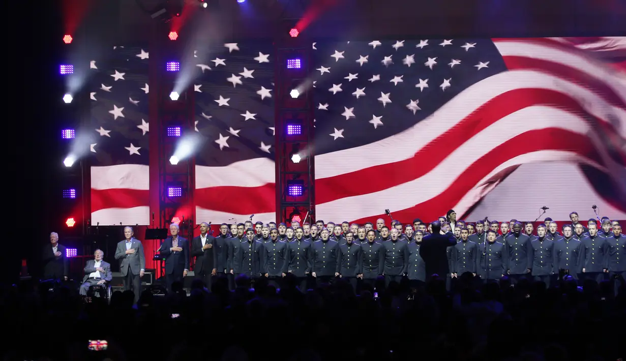 Lima mantan Presiden AS Jimmy Carter, George H.W. Bush, George W. Bush, Bill Clinton dan Barack Obama memegang dada mereka saat menyanyikan lagu kebangsaan AS dalam pembukaan konser amal di College Station, Texas (21/10). (AP Photo/LM Otero)