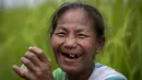 Seorang wanita suku Karbi tersenyum saat dia istirahat minum teh saat memanen padi di sebuah ladang di pinggiran Gauhati, India, Senin (23/5/2022). Suku Karbi adalah salah satu komunitas etnis utama di India Timur Laut yang sebagian besar terkonsentrasi di distrik perbukitan Karbi Anglong di Assam. (AP Photo/Anupam Nath)