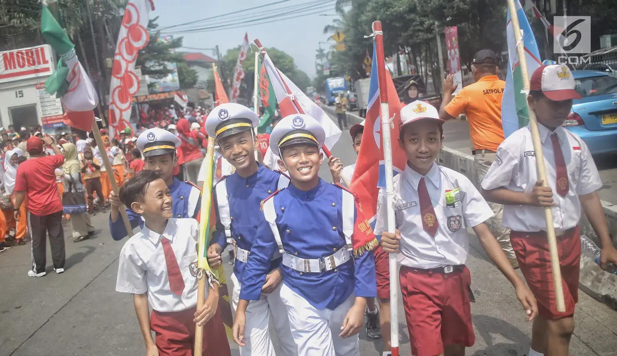 Siswa-siswi SD membawa bendera negara peserta Asian Games 2018 untuk menyambut Kirab Obor di kawasan Jati Padang, Pasar Minggu, Rabu (15/8). Mereka memenuhi jalanan untuk menyaksikan langsung Pawai Obor Asian Games 2018. (Liputan6.com/Faizal Fanani)
