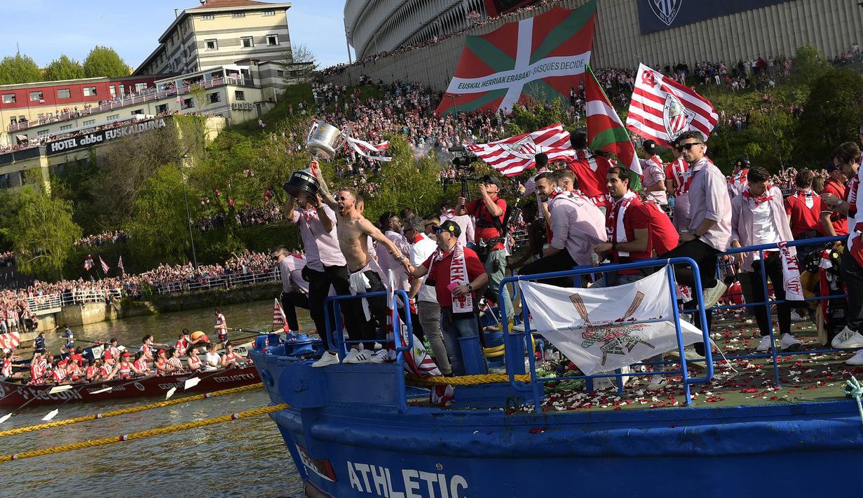 Pemain Athletic Bilbao, Iker Muniain, mengangkat trofi saat melakukan pawai perayaan juara Copa del Rey dengan menyusuri Sungai Nervion, Bilbao, Jumat (12/4/2024). (AP Photo/Alvaro Barrientos)