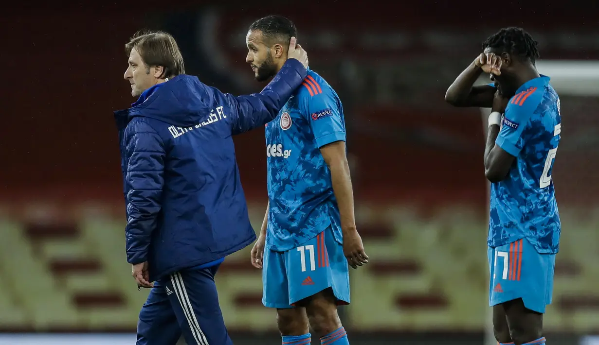 Manajer tim Olympiakos, Pedro Martins (kiri) menghibur striker Youssef El-Arabi usai laga leg kedua babak 16 besar Liga Europa 2020/2021 melawan Arsenal di Emirates Stadium, London, Kamis (18/3/2021). Olympiakos menang 1-0 atas Arsenal namun tetap tersingkir. (AP/Matt Dunham)