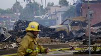 Petugas pemadam kebakaran berada di lokasi jatuhnya sebuah pesawat kecil jatuh di Santee, California, Senin (11/10/2021). Sedikitnya dua orang dikabarkan tewas meski kemungkinan akan bertambah ketika pesawat tersebut menabrak kawasan permukiman warga di California Selatan. (AP Photo/Gregory Bull)