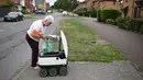 Sheila (71) mengambil kiriman dari robot otonom bernama Starship yang mengantarkan bahan makanan dari supermarket Co-op di Milton Keynes, Inggris, 20 September 2021. Robot Starship bertugas mengantarkan belanja dan makanan. (DANIEL LEAL-OLIVAS/AFP)