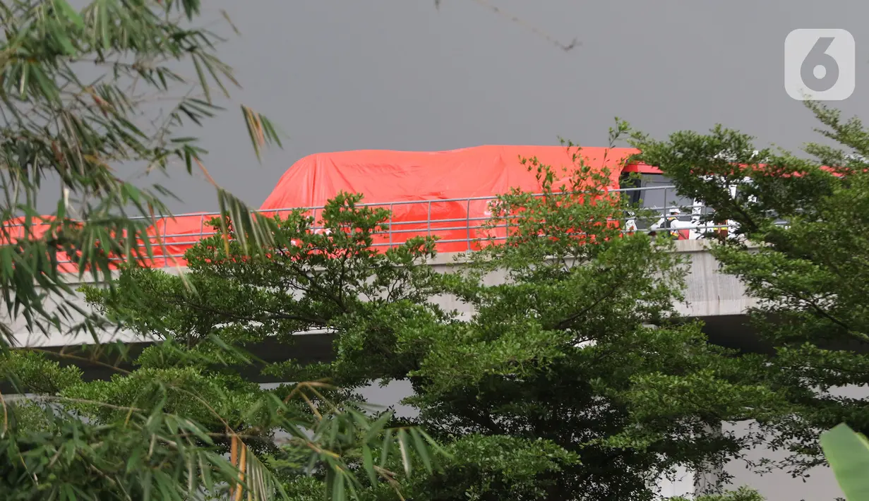 Terpal menutupi bagian gerbong kereta ringan lintas rel terpadu (LRT) Jabodebek yang mengalami kecelakaan di jalur lintas LRT Cibubur, Jakarta Timur, Senin (25/10/2021). Belum diketahui penyebab kecelakaan dan soal ada atau tidaknya korban. (Liputan6.com/Herman Zakharia)