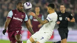 Gelandang West Ham United, Michail Antonio (kiri) berusaha mengontrol bola di depan bek Tottenham Hotspur, Cristian Romero pada laga pekan ke-31 Premier League 2023/2024 di London Stadium, London, Selasa (2/4/2024) malam. (AP Photo/Kirsty Wigglesworth)