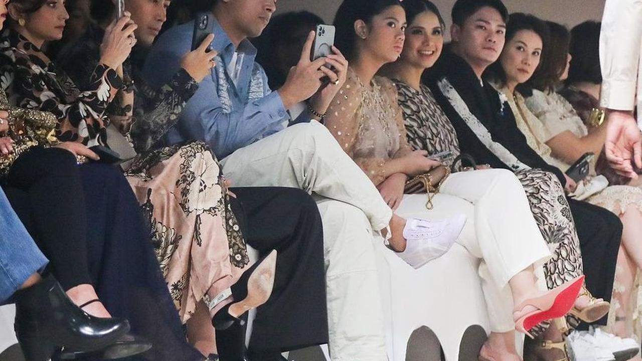 Ibu dan anak duduk berdampingan dengan serius melihat koleksi Spring Summer 2025 dari Biyan yang sedang dipertontonkan di atas catwalk.<br>