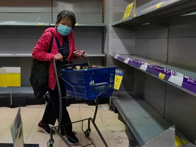 Warga mengenakan masker berjalan melewati rak kertas tisu yang kosong di sebuah supermarket di Hong Kong, Kamis (6/2/2020). Di tengah kelangkaan masker wajah untuk melindungi terhadap wabah virus corona, tisu toilet tiba-tiba juga menjadi salah satu barang yang langka di Hong Kong. (AP/Vincent Yu)
