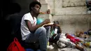 Seorang imigran tampak sedang makan di dekat stasiun kereta api Milan, 11 Juni 2015. Ratusan imigran yang baru diselamatkan beberapa pekan lalu dari laut oleh Italia ini hidup terlantar di sepanjang jalan. (REUTERS/Stefano Rellandini)