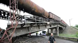  Meski terlihat berbahaya, beberapa orang dan pengemudi nekad melintasi kolong jembatan kereta yang rusak di dekat desa Novobakhmutivka, 30 km sebelah utara Donetsk, Ukraina, (8/7/2014). (AFP PHOTO/Dominique Faget)