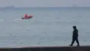 Seorang polisi berjalan di dermaga tidak jauh dari kecelakaan pesawat militer Rusia Tu-154 di Laut Hitam di pinggiran Sochi, Rusia (25/12). Sebanyak 91 penumpang belum diketemukan dalam kecelakaan pesawat. (REUTERS/Maxim Shemetov)