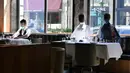 Pramusaji menata meja di dekat maneken yang diletakkan untuk menjaga jarak di sebuah restoran di Old Montreal, Kanada pada 10 Juli 2020. Restoran ini menempatkan maneken untuk menjaga jarak konsumen dan didandani dengan baju-baju keluaran terkini yang dapat dibeli pengunjung. (Eric THOMAS/AFP)