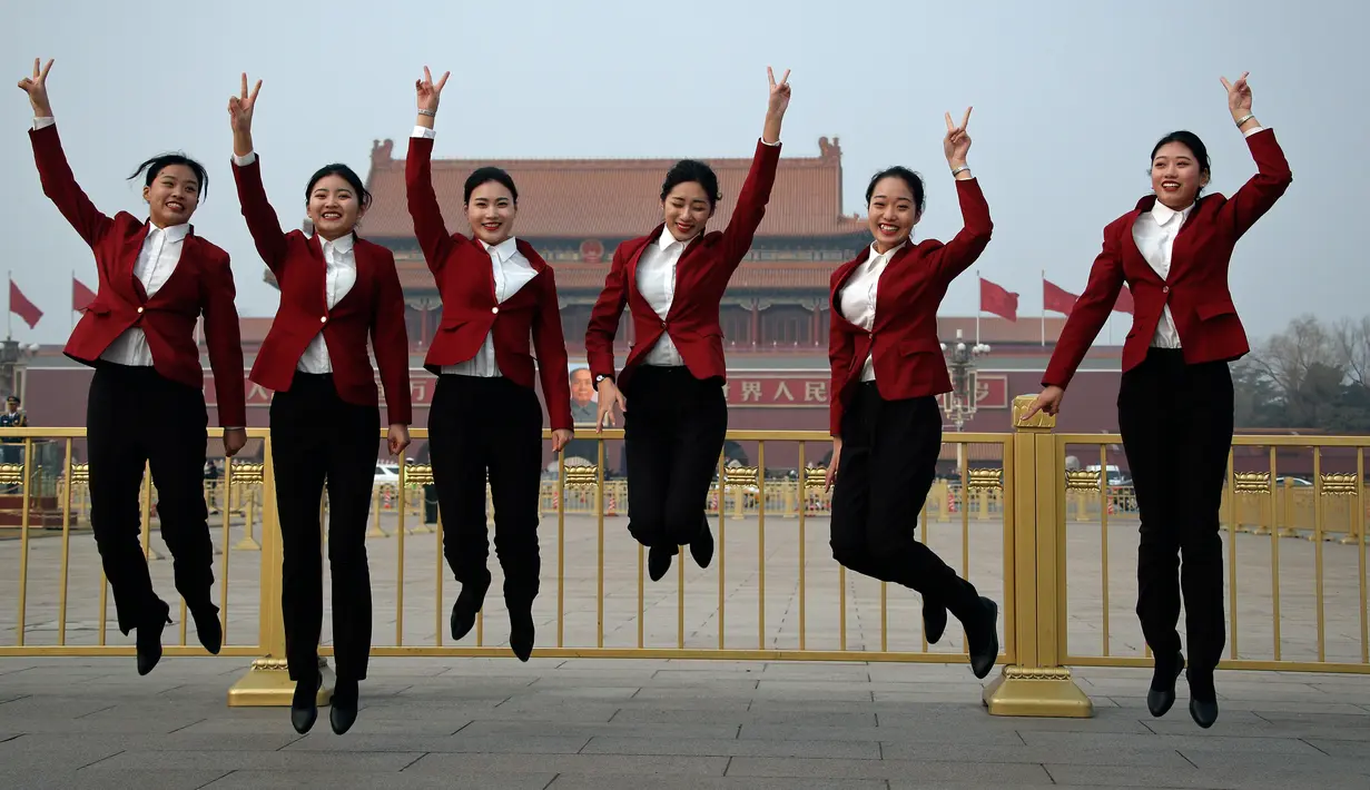 Sejumlah wanita berpose dengan latar belakang Istana Kuno Dinasti Ming dan Qing saat menyambut peserta Kongres Rakyat Nasional di Beijing, China, Minggu (3/3). Kongres ini dihadiri ribuan delegasi dari seluruh China. (AP Photo/Andy Wong)