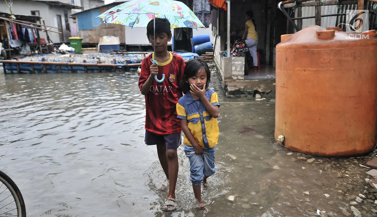 Dua orang anak melintasi banjir rob di permukiman Muara Angke, Jakarta, Selasa (22/1). Banjir air laut pasang atau Rob yang kembali melanda kawasan itu sejak 6 hari lalu membuat aktivitas warga sekitar terganggu. (Merdeka.com/Iqbal S. Nugroho)