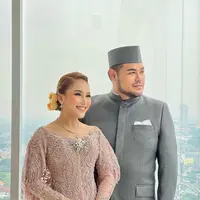 Di momen resepsi, Ayu Ting Ting berganti pakaian menjadi kebaya warna pink berhiaskan payet. Tampilannya tersebut juga serasi dengan Ivan yang mengenakan beskap abu-abu dan kain batik warna pink. (Instagram/ivan_gunawan).