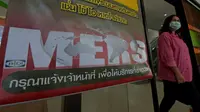 Seorang wanita Thailand berjalan memakai masker melewati pengumuman wabah MERS di Nonthaburi, Thailand, (19/6/2015). Pemerintah Thailand mengumumkan bahwa seorang pria 75 tahun asal Oman positif terjangkit virus MERS. (AFP PHOTO/Pornchai KITTIWONGSAKUL)