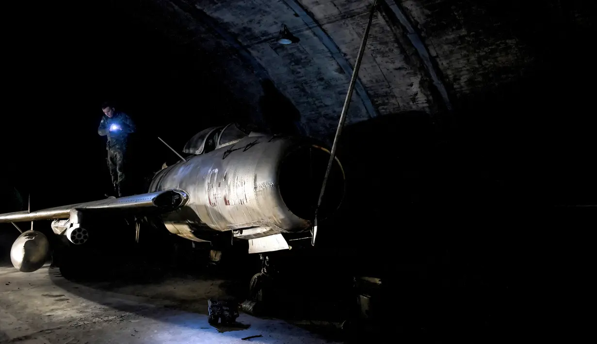 Seorang perwira militer Albania memeriksa pesawat tempur MIG-19 dalam terowongan utama Pangkalan Udara Gjader di dekat Kota Lezhe, 5 Februari 2019. Albania berencana menjual puluhan pesawat tempur yang terparkir di Pangkalan Udara Gjader. (Gent Shkullaku/AFP)