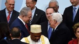 PM Israel Benjamin Netanyahu (kiri) berjabat tangan dengan Presiden Palestina Mahmud Abbas di depan Presiden Selandia Baru disela foto bersama pada KTT Perubahan Iklim, Conference of Parties (COP) 21 di Prancis, Senin (30/11). (AFP/POOL/MARTIN BUREAU)