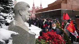Pendukung komunis meletakkan bunga di makam pemimpin Soviet Josef Stalin menandai peringatan 142 tahun kelahirannya di dekat Tembok Kremlin di Lapangan Merah dengan makam Lenin di sebelah kanan, di Moskow, Rusia, Selasa (21/12/2021). (AP Photo/Alexander Zemlanichenko)