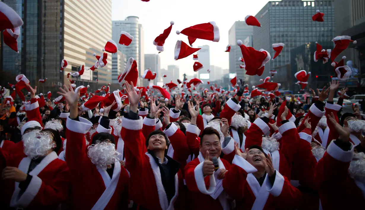 Sejumlah orang berpakaian seperti Santa Claus membuang topi mereka ke udara selama acara amal Natal di pusat kota Seoul, Korea Selatan, (24/12/2015). (REUTERS/Kim Hong-Ji)