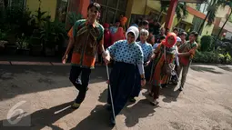 Penyandang disabilitas berbaris dibantu panitia menuju lokasi untuk menggunakan hak pilihya dalam Pilkada Putaran kedua di TPS 07 Kelurahan Cawang, Jakarta, Rabu (19/4). (Liputan6.com/Gempur M. Surya)