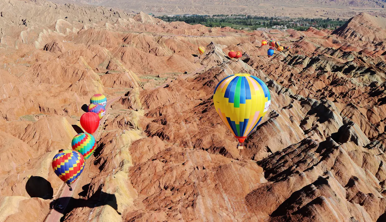 Sejumlah balon udara terbang di atas Taman Geologi Nasional Danxia di Zhangye, Provinsi Gansu, China barat laut, pada 26 Juli 2020. Sebuah festival balon udara internasional dibuka di Zhangye pada Minggu (26/7). Total 100 balon udara akan ditampilkan dalam festival tersebut. (Xinhua/Cheng Lin)