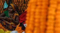 Seorang wanita membuat karangan bunga jelang Festival Diwali di pasar bunga New Delhi, India, Minggu (31/10/2021). Festival Diwali atau Festival Cahaya dalam agama Hindu melambangkan kemenangan baik atas buruk. (Money SHARMA/AFP)