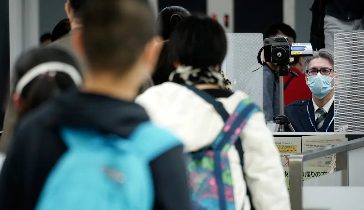 Petugas karantina (kanan) memantau para pelancong dari Wuhan China dan kota-kota lain ketika melewati pemindai suhu tubuh di Bandara Internasional Narita, Narita, Tokyo, Kamis (23/1/2020). Jepang meningkatkan pengamanan untuk mewaspadai penyebaran virus corona asal China. (AP Photo/Eugene Hoshiko)