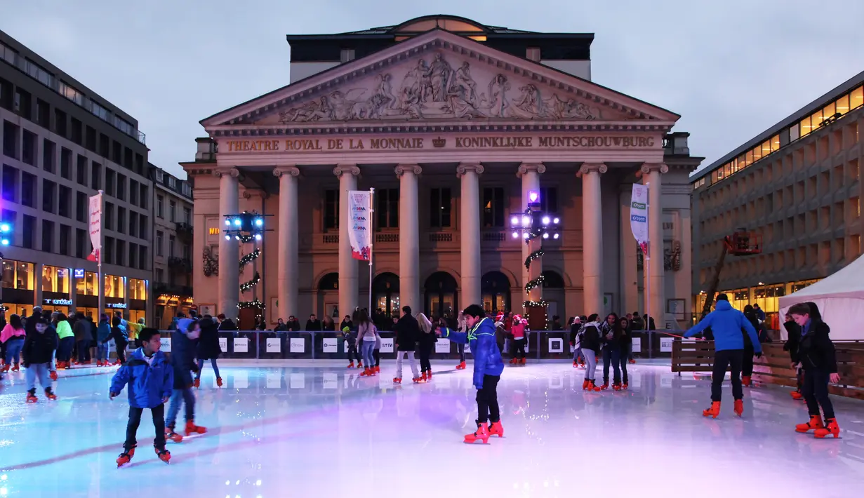 Pengunjung bermain Ice Skating di depan Theater Royal De La Monnaie saat mengunjungi pasar malam Natal khas Eropa atau Christmas Market di pusat kota Brussels, Belgia, Senin (14/12/2015). (Arie Asona)