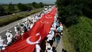 Ribuan pendukung partai oposisi utama Turki, Partai Rakyat Republik (CHP) berjalan kaki sambil membentangkan bendera nasional di Sakarya, Turki (1/7). Mereka membentangkan bendera Turki sepanjang 1.100 meter. (AFP Photo/ Ziya Koseoglu)