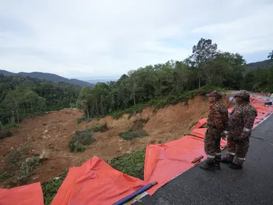 Anggota tim pemadam kebakaran dan penyelamat melihat tanah longsor di Batang Kali, Malaysia, Sabtu, 17 Desember 2022. Longsor Jumat, 16 Desember 2022, di sebuah perkemahan wisata di Malaysia menyebabkan lebih dari selusin orang tewas dan pihak berwenang mengatakan belasan orang lainnya dikhawatirkan terkubur di lokasi di sebuah pertanian organik di luar ibu kota Kuala Lumpur. (AP Photo/Vincent Thian)