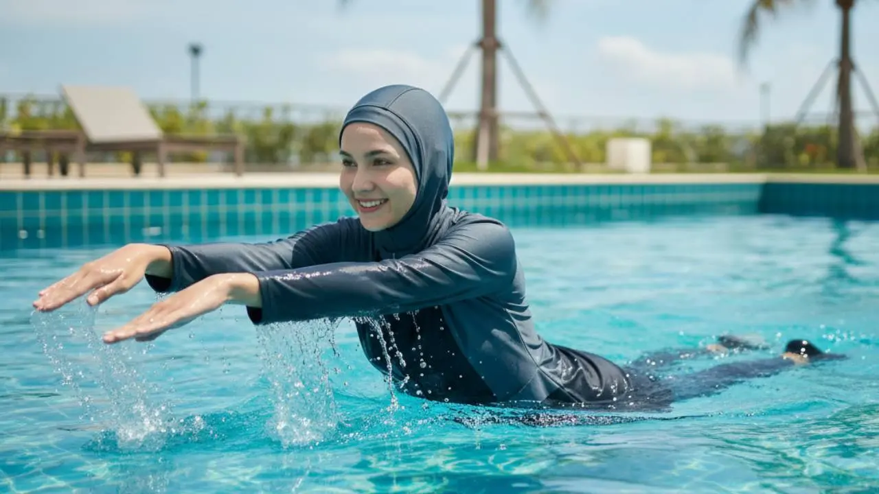 Ilustrasi perempuan muslimah berenang.