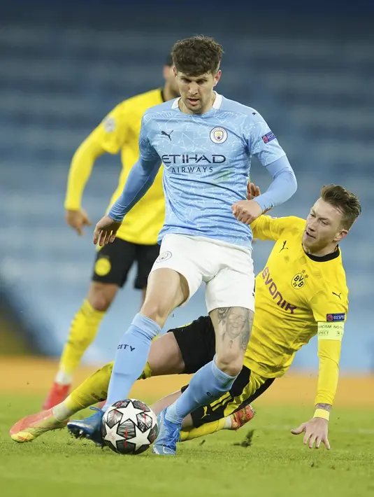 Penyerang Borussia Dortmund, Marco Reus berebut bola dengan bek Manchester City, John Stones pada leg pertama perempat final Liga Champions di Etihad Stadium, Rabu (7/4/2021) dini hari WIB. Man City menang 2-1 atas Dortmund. (AP Photo/Dave Thompson)