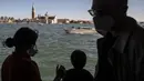 Turis, yang mengenakan masker, duduk di atas vaporetto atau bus air di Venesia pada 20 Mei 2021.  Wisatawan kembali berdatangan menikmati keindahan Venesia, yang sering dijuluki kota paling romantis di dunia, setelah Italia menghapus kewajiban karantina bagi pendatang. (Marco Bertorello/AFP)