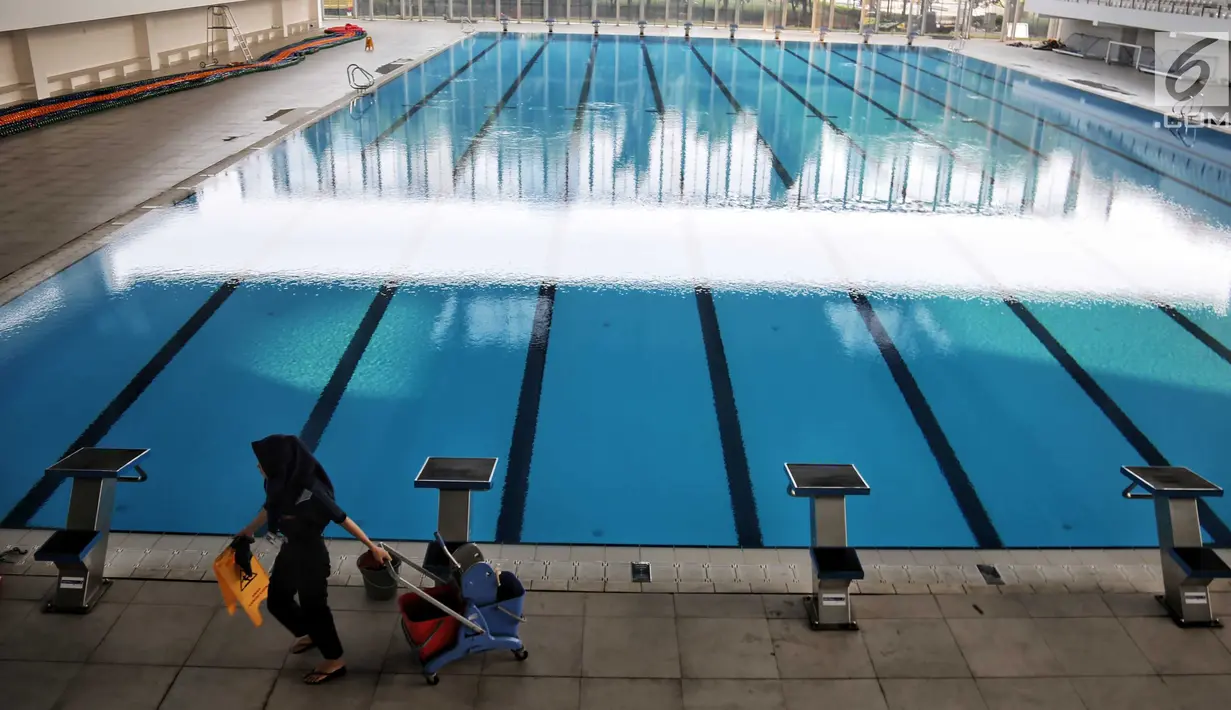 Petugas kebersihan berjalan dekat kolam Stadion Akuatik Gelora Bung Karno (GBK), Jakarta, Rabu (11/7). Stadion ini memiliki 3 kolam utama dan 1 kolam pemanasan berstandar Olimpiade dari FINA (Federasi Renang Internasional). (Liputan6.com/Faizal Fanani)