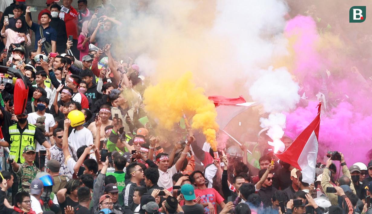 Sejumlah masyarakat menyalakan bom asap  saat menyambut Timnas Indonesia U-22 dan kontingen Indonesia untuk SEA Games 2023 saat pawai Kira87uara yang berlangsung dari Kemenpora hingga GBK, Jakarta, Jumat (19/05/2023). (Bola.com/M Iqbal Ichsan)