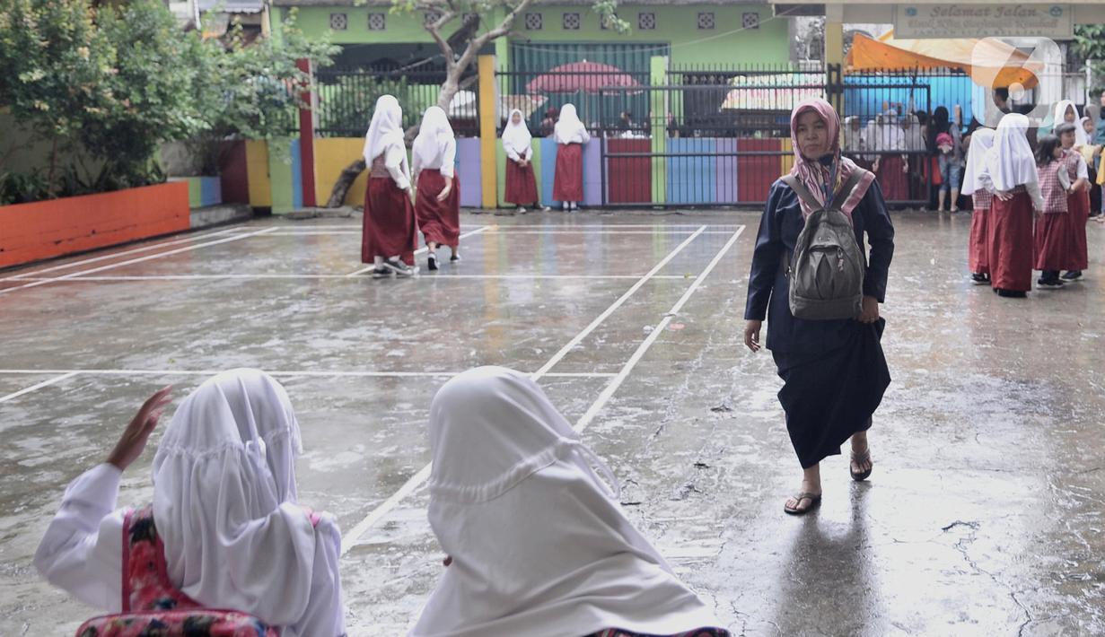 Seorang guru mengenakan sandal akibat sepatu rusak oleh banjir di SDN Bukit Duri 11, Jakarta, Senin (6/1/2020). Banjir menyebabkan sekitar 50 persen siswa SDN Bukit Duri 11 tidak masuk sekolah karena mayoritas tinggal di kawasan Kampung Melayu dan Kampung Pulo. (merdeka.com/Iqbal S. Nugroho)