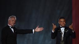 Striker PSG, Kylian Mbappe (kanan) bereaksi setelah menerima penghargaan Trophee Kopa pada seremoni Ballon d'Or 2018 di Paris, Senin (3/12). Mbappe menjadi pemain pertama dalam sejarah yang memenangi penghargaan Trophee Kopa. (FRANCK FIFE/AFP)