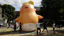 Aktivis mengembangkan balon berbentuk bayi Presiden AS Donald Trump di Bingfield Park, London, 10 Juli 2018. Balon bayi atau disebut Trump Baby itu akan diterbangkan ketika Trump melakukan lawatan perdana ke Inggris pada Kamis (12/7).  (AP /Matt Dunham)