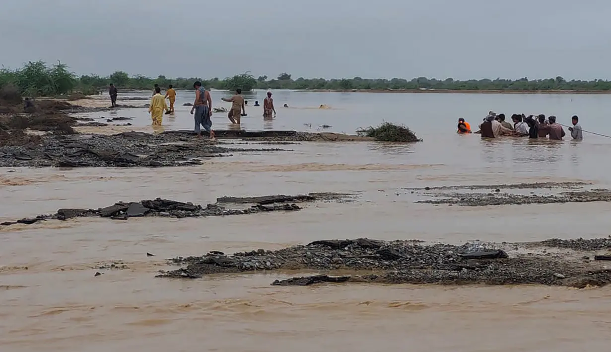 Petugas penyelamat membantu penduduk desa untuk mengevakuasi mereka dari daerah banjir yang disebabkan hujan lebat, di Lasbella, sebuah distrik di provinsi Baluchistan barat daya Pakistan (26/7/2022). Para pejabat mengatakan, pada hari Rabu, penyelamat yang didukung oleh pasukan menggunakan perahu dan helikopter untuk mengungsi ratusan orang terdampar dari barat daya Pakistan, di mana banjir yang dipicu oleh hujan telah menewaskan 104 orang sejak bulan lalu. (AP Photo/Hamdan Khan)