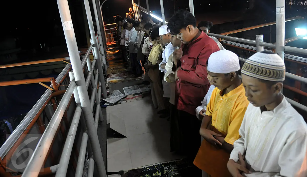 Puluhan warga melaksanakan ibadah Salat Tarawih pertama di kawasan Pasar Gembrong, Jakarta, Rabu (17/6/2015). Terbatasnya jumlah daya tampung musholla membuat warga terpaksa salat di jembatan. (Liputan6.com/Johan Tallo)