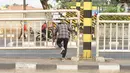 Warga menerobos celah pagar pembatas jalan di depan Stasiun Pasar Minggu, Jakarta, Rabu (16/10/2019). Jauhnya jembatan penyeberangan orang (JPO) membuat warga memanfaatkan celah pagar pembatas tersebut sebagai akses menyeberang, meski berbahaya bagi keselamatan. (Liputan6.com/Immanuel Antonius)