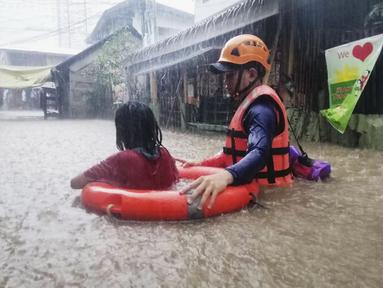 Penyelamat membantu seorang gadis saat mengarungi banjir yang disebabkan Topan Rai di Kota Cagayan de Oro, Filipina selatan, Kamis (16/12/2021). Puluhan ribu orang sedang dievakuasi ke tempat yang aman ketika Topan Rai mendekati pada Kamis (16/12). (Philippine Coast Guard via AP)