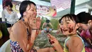 Seorang wanita dan putrinya menempelkan cokelat ke wajah mereka saat mandi spa cokelat di Hakone, Jepang, Senin (13/2). Mandi spa cokelat diadakan dalam rangka menyambut Hari Valentine. (AFP PHOTO / Kazuhiro Nogi)