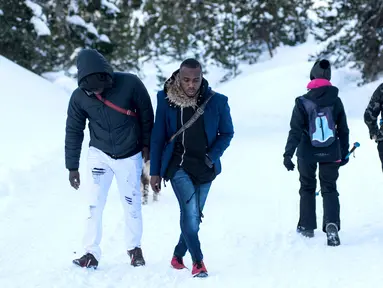 Dua imigran dari Pantai Gading berjalan menuju Colle della Scala (Col de l'Echelle) sebuah jalan yang tertutup salju, untuk melintasi perbatasan antara Italia dan Prancis di Pegunungan Alpen, Italia (13/1). (AFP/Piero Cruciatti)