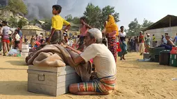 Pengungsi Rohingya menyelamatkan barang-barang mereka dan menyaksikan asap membubung menyusul kebakaran di kamp pengungsi Rohingya di Balukhali, Bangladesh selatan (22/3/2021). Kebakaran tersebut diperkirakan menghancurkan 900 tenda tempat ribuan pengungsi berlindung. (AP Photo/Shafiqur Rahman)