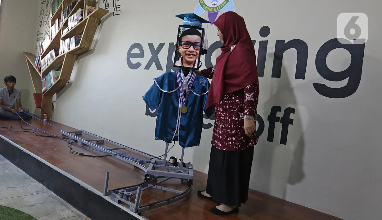 Kepala Sekolah mengalungkan piagam wisuda kepada siswa Kelompok Bermain Taman Kanak-kanak (KB TK) Sekolah Nasional Satu (Nassa School) di Bekasi, Rabu (1/07/2020). Sekolah itu menggunakan teknologi virtual dan roboda guna memudahkan prosesi wisuda di tengah Covid-19. (Liputan6.com/Herman Zakharia)