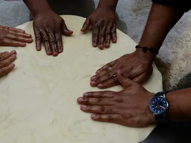 Koki India menyiapkan adonan untuk membuat roti goreng yang dikenal dengan sebutan Bhatura, India, New Delhi, Kamis (6/4). Penyelenggara berharap Bhatura buatan mereka bisa memecahkan rekor Bhatura  terbesar di India. (AFP PHOTO / SAJJAD HUSSAIN)