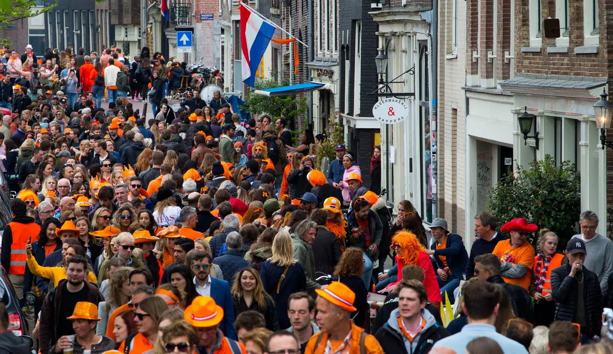 Orang-orang mengenakan atribut dan pakaian oranye mendominasi jalan pada Hari Ulang Tahun Raja atau King's Day di Amsterdam, Belanda, 27 April 2018. Di hari ini, jalanan dipenuhi dengan pesta yang meriah, serta banyak pasar-pasar unik. (AP/Peter Dejong)