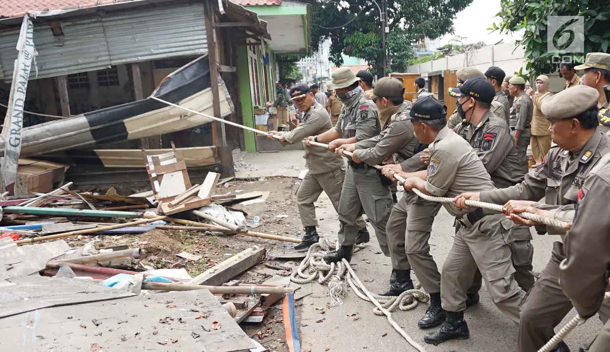 Petugas Satpol PP menarik tali untuk merobohkan bangunan liar di Jalan Desa Semanan, Kalideres, Jakarta Barat, Senin (9/4). Penertiban dilakukan karena bangunan liar tersebut berdiri di atas tanah saluran air. (Liputan6.com/Arya Manggala)