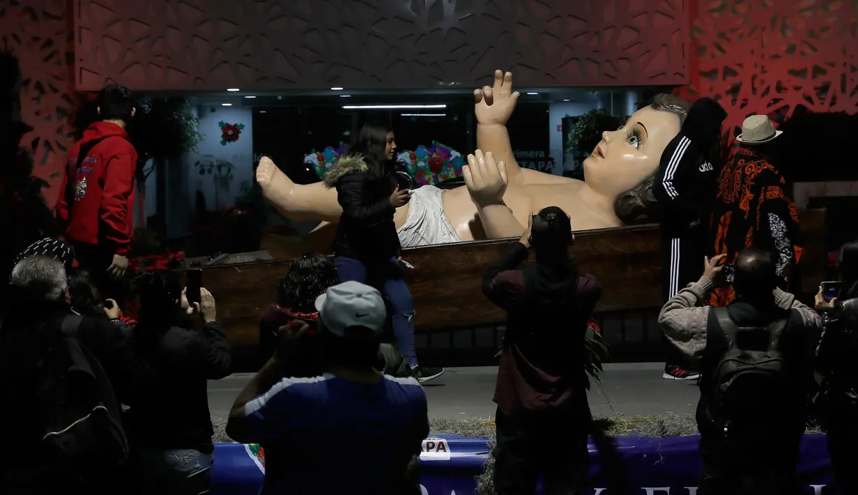 Orang-orang berkumpul dekat patung bayi Yesus raksasa di Mexico City, Meksiko, Senin (23/12/2019). Patung tersebut dipersiapkan untuk menyambut malam Natal. (AP Photo/Marco Ugarte)